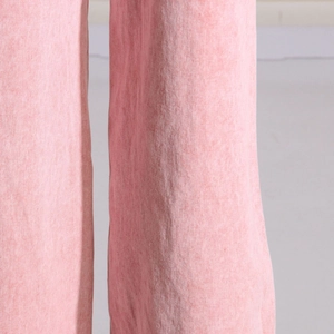 Detailansicht von rosa gewaschenem Denim mit Twill-Textur und sauberer Naht am Hosenbein