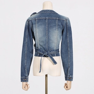 Detail view of the back of a cropped blue denim jacket featuring a lace-up bow design