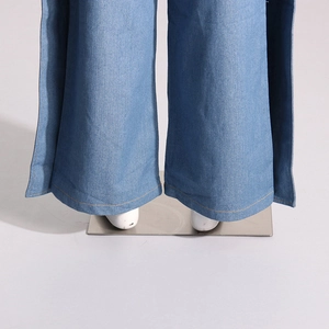 Gros plan du denim bleu clair avec doubles coutures orange sur l'ourlet du pantalon