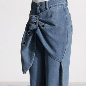 Detail of waist design with asymmetric wrap and metal buckle on wide-leg blue jeans