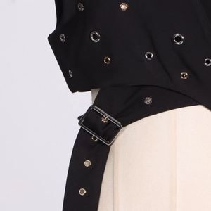 Close-up of black punk vest featuring silver eyelets and side buckle belt detail