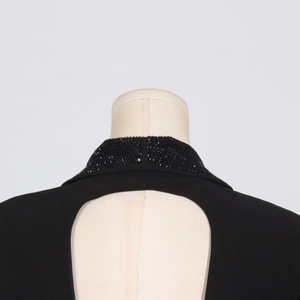 Dettaglio dello scollo con perline e apertura circolare sul retro del blazer nero