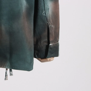 Detail of camoflage denim jacket showing distressed texture and drawstring hem