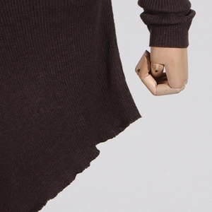 Detailed close-up of dark brown ribbed knit fabric with irregular hem and sleeve cuff