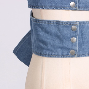 Detailansicht eines Denim-Oberteils mit metallischen Druckknöpfen und Doppelnaht