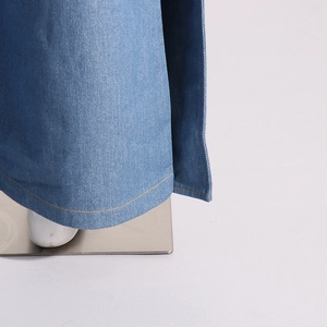 Détail du bas de pantalon en jean bleu clair avec coutures contrastées jaunes et texture