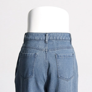 Detail of high-waist blue denim jeans featuring back pockets and neat stitching