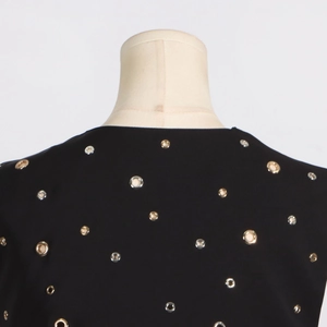 Detail of trendy black sleeveless top with gold and silver hand-stitched eyelet rivets