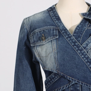 Macro detail of dark blue washed denim jacket with wrap design and flap pocket