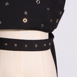Detailed view of black sleeveless top with silver metal grommets and waist belt decoration