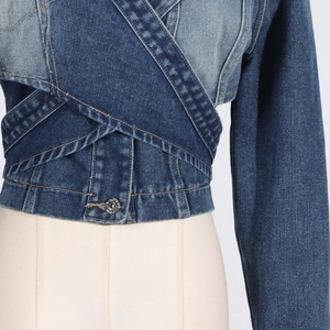 Detailed close-up of a color-block cropped denim jacket with asymmetrical overlap
