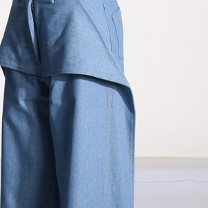 Vue détaillée du jean taille haute bleu avec taille asymétrique et surpiqûres orange