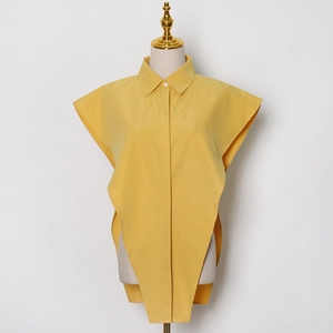 Dettaglio della camicia senza maniche giallo zenzero con orlo asimmetrico e spacco laterale