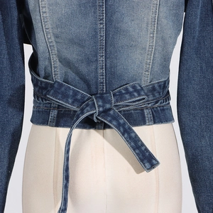 Detail of blue denim jacket showing a tied bow drawstring design on the back waist