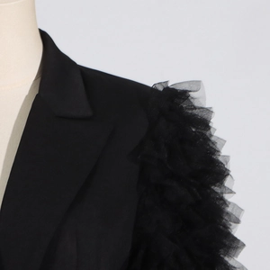 Detail of elegant black blazer with ruffled mesh tulle patchwork on the shoulder seams