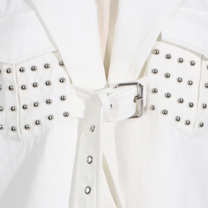 Detail eines weißen Denim-Blazers mit silbernen Nieten und Taillengürtel mit quadratischer Schnalle