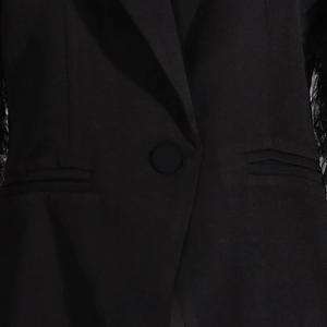 Detailed shot of black blazer featuring mesh splice sleeves and matching cloth button