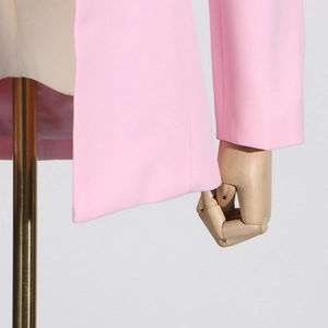 Detailed close-up of pink waist-cropped blazer hem and sleeve cuff craftsmanship