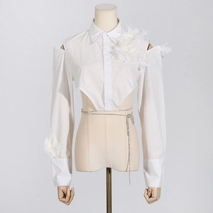 Detail der schulterfreien weißen Bluse mit Organza-Blumen und Paillettengürtel