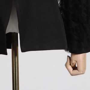 Detail of black blazer featuring ruched mesh sleeves and smooth tailored fabric