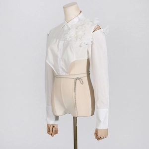 Detailansicht der weißen asymmetrischen Bluse mit Blumenapplikationen an der Schulter