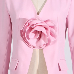 Detail of a pink blazer featuring a large 3D handmade fabric rose on the chest