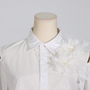 Makro-Detail des weißen Off-Shoulder-Tops mit 3D-Blumen-Feder-Verzierung und Perlen