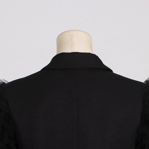 Detail view of the black blazer back featuring sheer mesh patchwork sleeves and lapel
