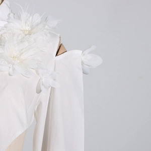 Detail der weißen schulterfreien Bluse mit 3D-Blumen, Perlen und weichen Federn