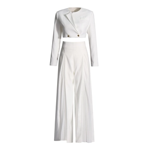 Détail d'un ensemble blanc deux pièces avec veste courte et pantalon large fendu