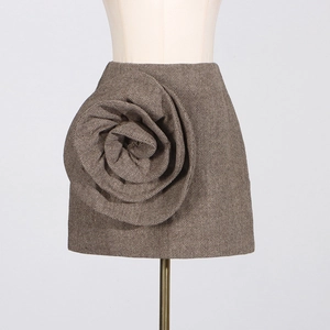 Close-up of brown herringbone skirt featuring a large 3D floral accent piece