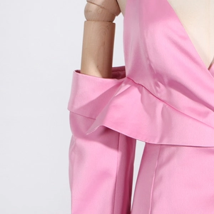 Détail d'un blazer en satin rose montrant le devant à volants et le design aux épaules dénudées