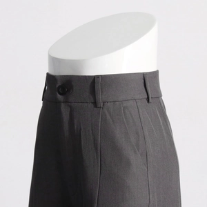 Détail du pantalon gris foncé à taille haute avec plis et passants de ceinture