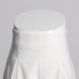 Gros plan sur le pantalon blanc taille haute avec plis frontaux et tissu structuré