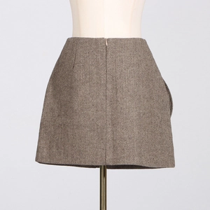 Detail of high-waist brown herringbone A-line mini skirt with textured wool fabric