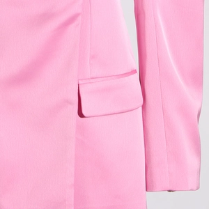 Vue détaillée de la poche à rabat et du tissu rose bonbon lisse sur le blazer cintré