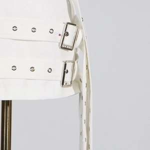 Detail eines weißen Blazers mit industriellen Metallösen und silbernen Schnallen