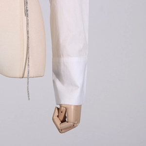 Detail der weißen Hemdmanschette mit silberner Strasskette und mehrschichtigem Design