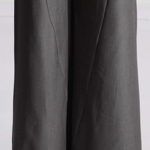 Vue détaillée du pantalon large gris foncé montrant le tissu tissé et son beau tombé