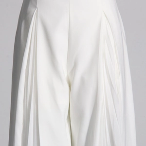 Détail du pantalon blanc à taille haute présentant des plis plats profonds symétriques