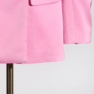 Gros plan du blazer rose vif montrant la couture de l'ourlet et la qualité du tissu texturé