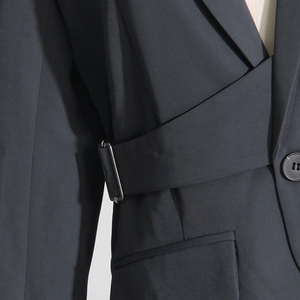 Detail of waist metal buckle and crossed strap design on slim fit gray blazer