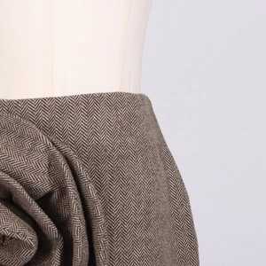 Detail of high-waist herringbone skirt featuring a large 3D fabric flower decoration