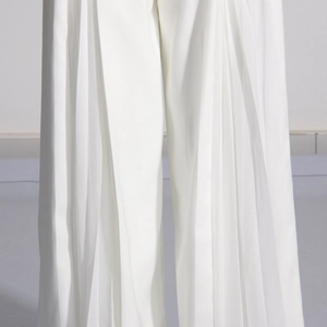 Détail du pantalon blanc à jambes larges montrant le plissé et le tissu fluide