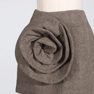 Detail of a brown herringbone wool skirt featuring a large 3D handmade rose decoration