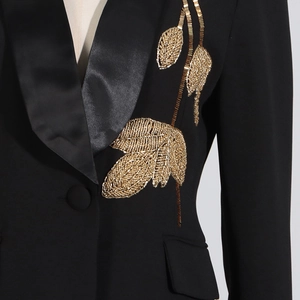 Detailed view of luxury gold leaf bead embroidery on a black satin lapel blazer