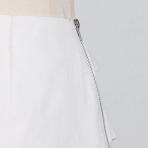 Detailaufnahme des seitlichen silbernen Metallreißverschlusses auf weißer Twill-Hose