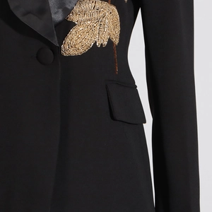 Detail of elegant gold leaf embroidery and satin lapel on a black fashion blazer