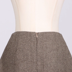 Close-up of brown herringbone fabric texture and hidden zipper on high-waist A-line skirt