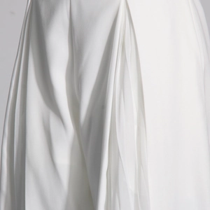 Gros plan du pantalon large blanc montrant des plis superposés et des détails en mesh